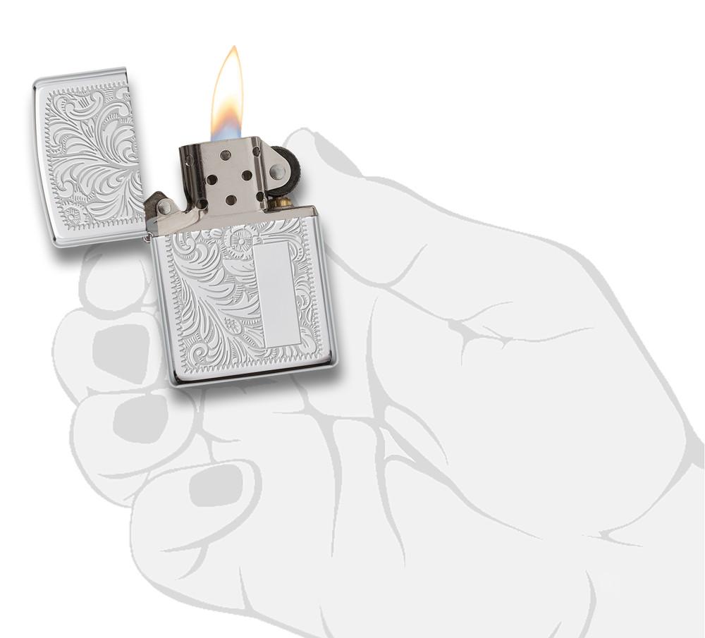Frontansicht Zippo Feuerzeug High Polish Chrome mit venezianischem Design und Initialplatte geöffnet mit Flamme in stilistischer Hand