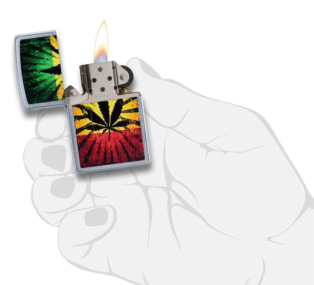 Zippo Feuerzeug chrom mit Hanfblatt auf Jamaikafarben Hintergrund geöffnet mit Flamme in stilisierter Hand