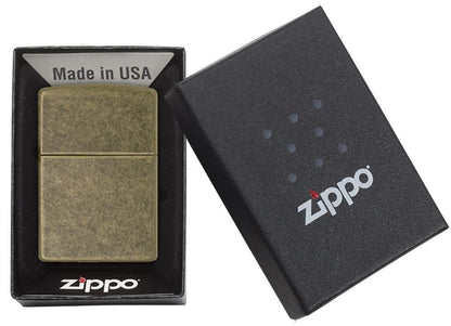 Ein messingfarbenes Zippo-Feuerzeug liegt in einer schwarzen Schachtel mit der Aufschrift "Made in USA", während der Deckel der Schachtel seitlich geöffnet ist.