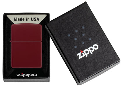 Ein weinrotes Zippo-Feuerzeug liegt in einer offenen schwarzen Schachtel mit der Aufschrift "Made in USA" und "Zippo".
