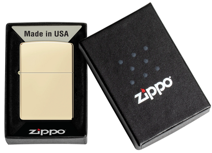 Ein goldfarbenes Zippo-Feuerzeug liegt geöffnet in einer schwarzen Schachtel mit der Aufschrift "Made in USA" und "Zippo", daneben der passende Schachteldeckel.